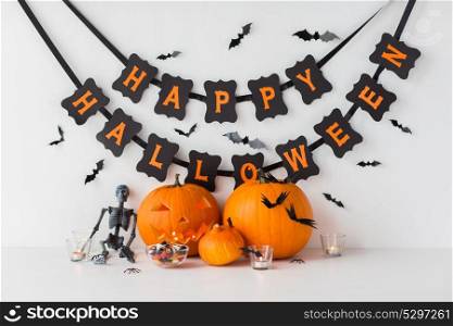 halloween, holidays and decoration concept - jack-o-lantern or carved pumpkins with candies and festive garland on white background. carved pumpkins with candies and halloween garland
