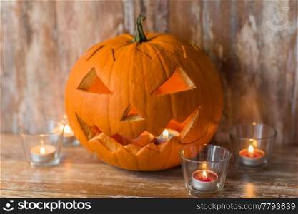 halloween, holidays and decoration concept - jack-o-lantern or carved pumpkins with candles on wooden table at home. jack-o-lantern or carved halloween pumpkin