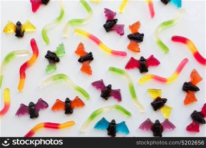 halloween, junk food and confectionery concept concept - multicolored gummy worms and bet candies over white background. gummy worms and bet candies for halloween party