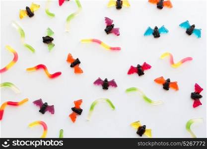 halloween, junk food and confectionery concept concept - multicolored gummy worms and jelly bet candies over white background. gummy worms and bet candies for halloween party
