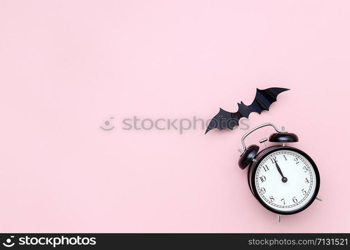 Halloween night concept. Black alarm clock and flying bat on pink background. Creative flat lay, top view, copy space, template for yuor design, greeting card, invitation.. Halloween night concept. Black alarm clock and flying bat on pink background. Creative flat lay, top view, copy space, template for yuor design, greeting card, invitation