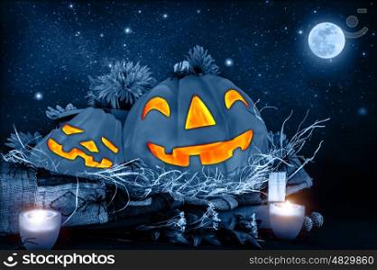 Halloween night, scary carved pumpkin head glowing in dark starry night, full moon, traditional october holiday, horror concept