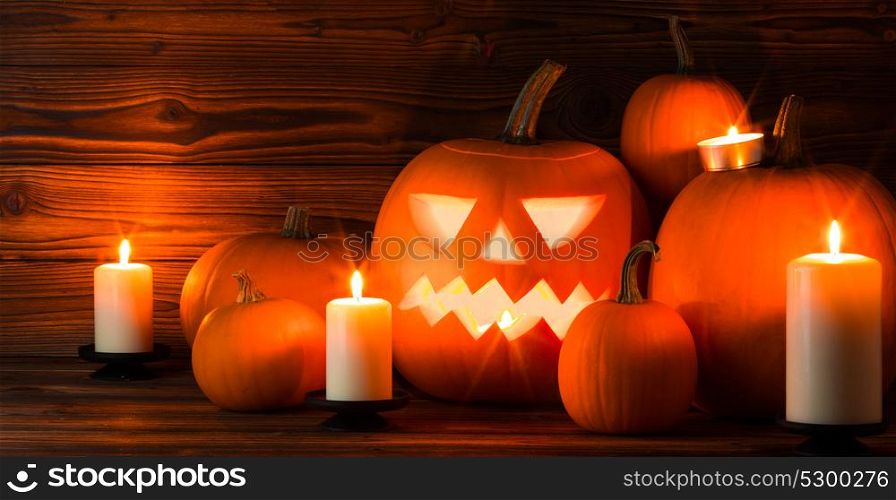 Halloween pumpkin and candles. Halloween pumpkin head jack lantern and candles on wooden background