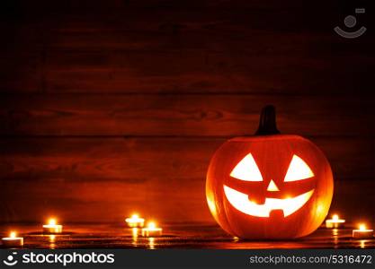 Halloween pumpkin and candles. Halloween pumpkin head jack o lantern and candles on wooden background