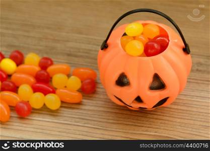 Halloween pumpkin basket full of candies on a wooden background