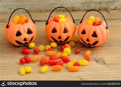 Halloween pumpkin baskets full of candies on a wooden background