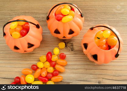 Halloween pumpkin baskets full of candies on a wooden background