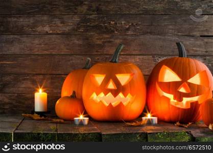 Halloween pumpkin head jack lantern and candles on wooden background. Halloween pumpkin and candles