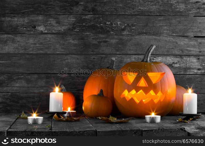 Halloween pumpkin head jack lantern and candles on wooden background. Halloween pumpkin and candles