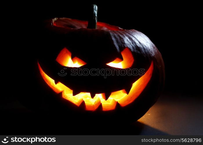 Halloween pumpkin head jack lantern with scary evil face on black