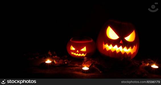 Halloween pumpkin head jack o lantern and candles on wooden background. Halloween pumpkin and candles