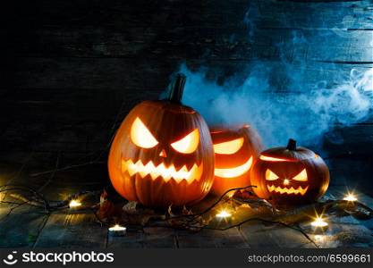 Halloween pumpkin head jack o lantern and candles on wooden background. Halloween pumpkin and candles