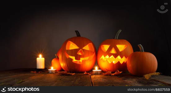 Halloween pumpkin head jack o lantern and candles on wooden background. Halloween pumpkin and candles