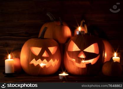 Halloween pumpkin head lanterns and burning candles on wooden background. Halloween pumpkins and candles