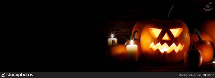 Halloween pumpkin head lanterns and burning candles on wooden background isolated on black. Halloween pumpkins and candles