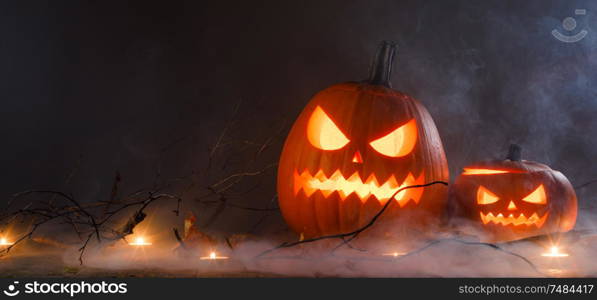 Halloween pumpkin heads jack o lantern and candles in fog on wooden background. Halloween pumpkins and candles