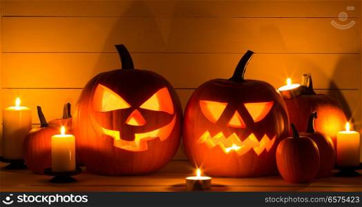 Halloween pumpkin heads jack o lantern and candles on wooden background. Halloween pumpkins and candles