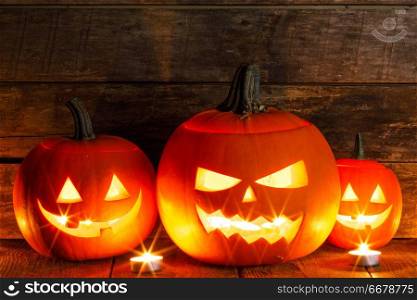 Halloween pumpkin heads jack o lantern and candles on wooden background. Halloween pumpkins and candles