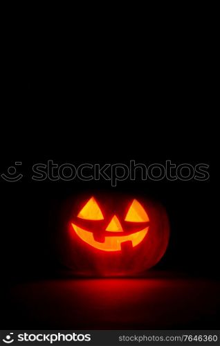 halloween pumpkin in the dark with candle inside, black background with copy space. Halloween pumpkin in the dark