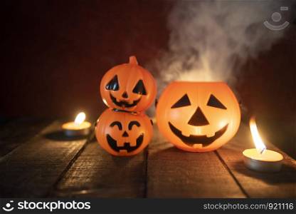 Halloween pumpkin lantern candle light on wooden with smoke / head jack o lantern funny spooky holiday decorate on halloween background