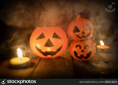 Halloween pumpkin lantern candle light on wooden with smoke / head jack o lantern funny faces spooky holiday decorate on halloween background