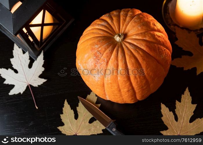 Halloween pumpkin lantern on table with Jack o&rsquo;Lantern face with fallen autumn leaves and candles.. Halloween pumpkins or Jack o&rsquo;Lantern