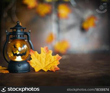 Halloween pumpkin on Autumn leaves and Jack o lantern on brown wooden background texture, Halloween,Fall and October concept copy space. Halloween pumpkin on Autumn leaves and Jack o lantern on brown wooden background texture, Halloween,Fall and October concept