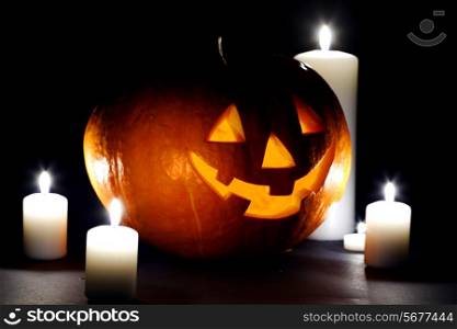 Halloween pumpkin surrounded with candles isolated on black background