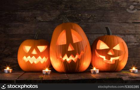 Halloween pumpkins and candles. Halloween pumpkin heads jack o lantern and candles on wooden background