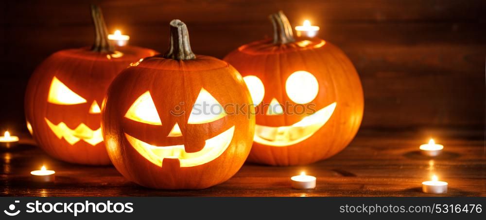 Halloween pumpkins and candles. Halloween pumpkin heads jack o lantern and candles on wooden background