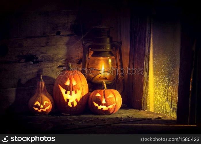 Halloween pumpkins and lantern in an old house by the window where the moonlight shines.