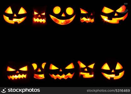 Halloween Pumpkins on black. Many Halloween Pumpkin glowing faces in a row isolated on black background