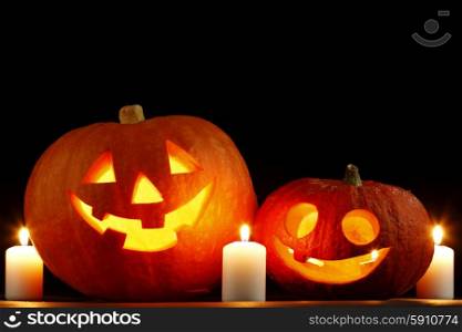 Halloween pumpkins surrounded with candles isolated on black background