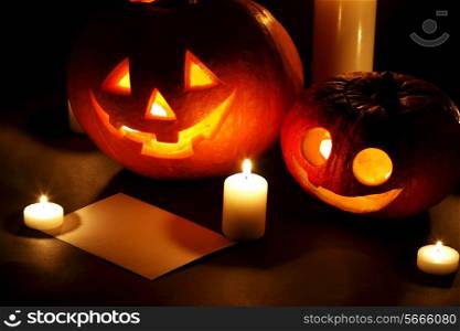 Halloween pumpkins with candles and post card isolated on black background