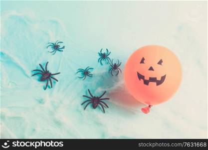Halloween scene with scary balloon and spiders in web on blue, retro toned. Halloween scene with balloons