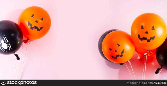 Halloween scene with two orange and black balloons on pink background. Halloween scene with balloons