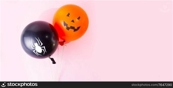 Halloween scene with two orange and black balloons on pink background. Halloween scene with balloons