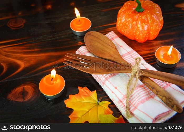 Halloween table setting decoration accessories holiday with pumpkin leaves autumn on dark wood background and spoon fork on table with candle , halloween dinner