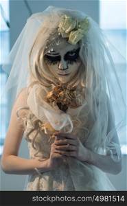 Halloween witch. Beautiful bride woman wearing santa muerte mask and wedding dress holding dead bouquet of roses