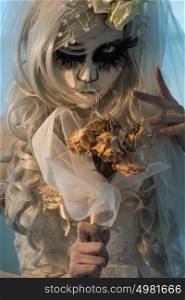 Halloween witch. Beautiful bride woman wearing santa muerte mask and wedding dress holding dead bouquet of roses