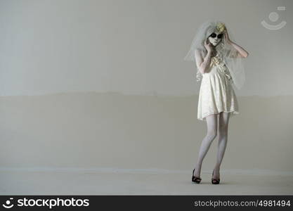 Halloween witch. Beautiful woman wearing santa muerte mask and wedding dress posing full length