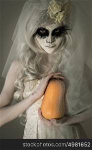 Halloween witch. Beautiful woman wearing santa muerte mask holding pumpkin