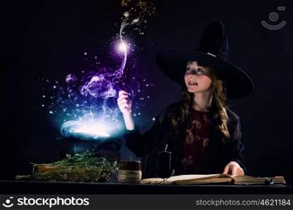 Halloween witch. Little Halloween witch making magic with stick
