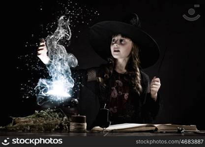 Halloween witch. Little Halloween witch making magic with stick