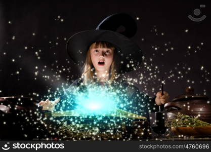 Halloween witch. Little Halloween witch making magic with stick