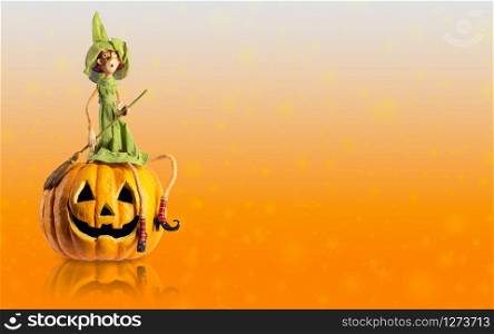 Halloween Witch sit on carved Pumpkin with magic lights at orange background. Copy space
