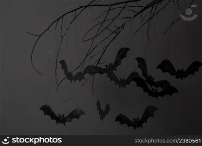 halloween with silhouettes of black bats on a tree branch on a dark background. halloween and a lot of bats