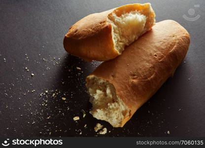 halved bread roll with crumbs on black background. halved bread roll with crumbs