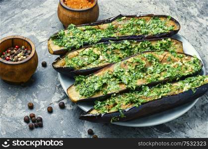 Halved homemade eggplant with garlic and parsley.Fried eggplant with herbs.Vegetarian food.. Halved baked eggplant