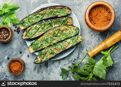 Halved homemade eggplant with garlic and parsley.Fried eggplant with herbs.Vegetarian food.. Halved baked eggplant